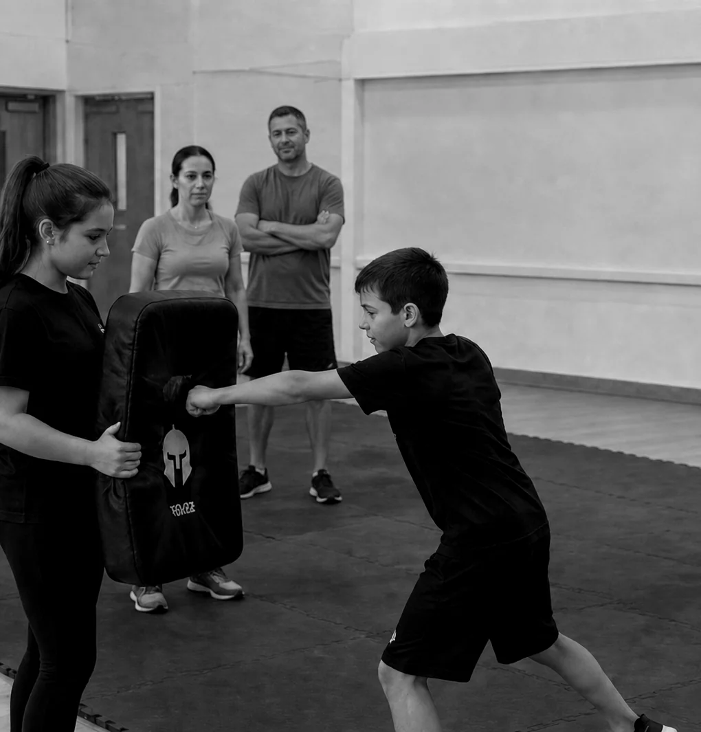 A young person practising a controlled pad strike while parents watch a StreetReady family workshop